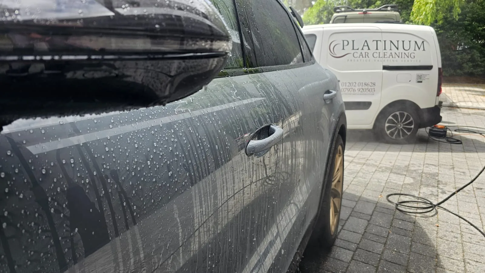 Water beading on a grey car with the Platinum Car Cleaning van in the background